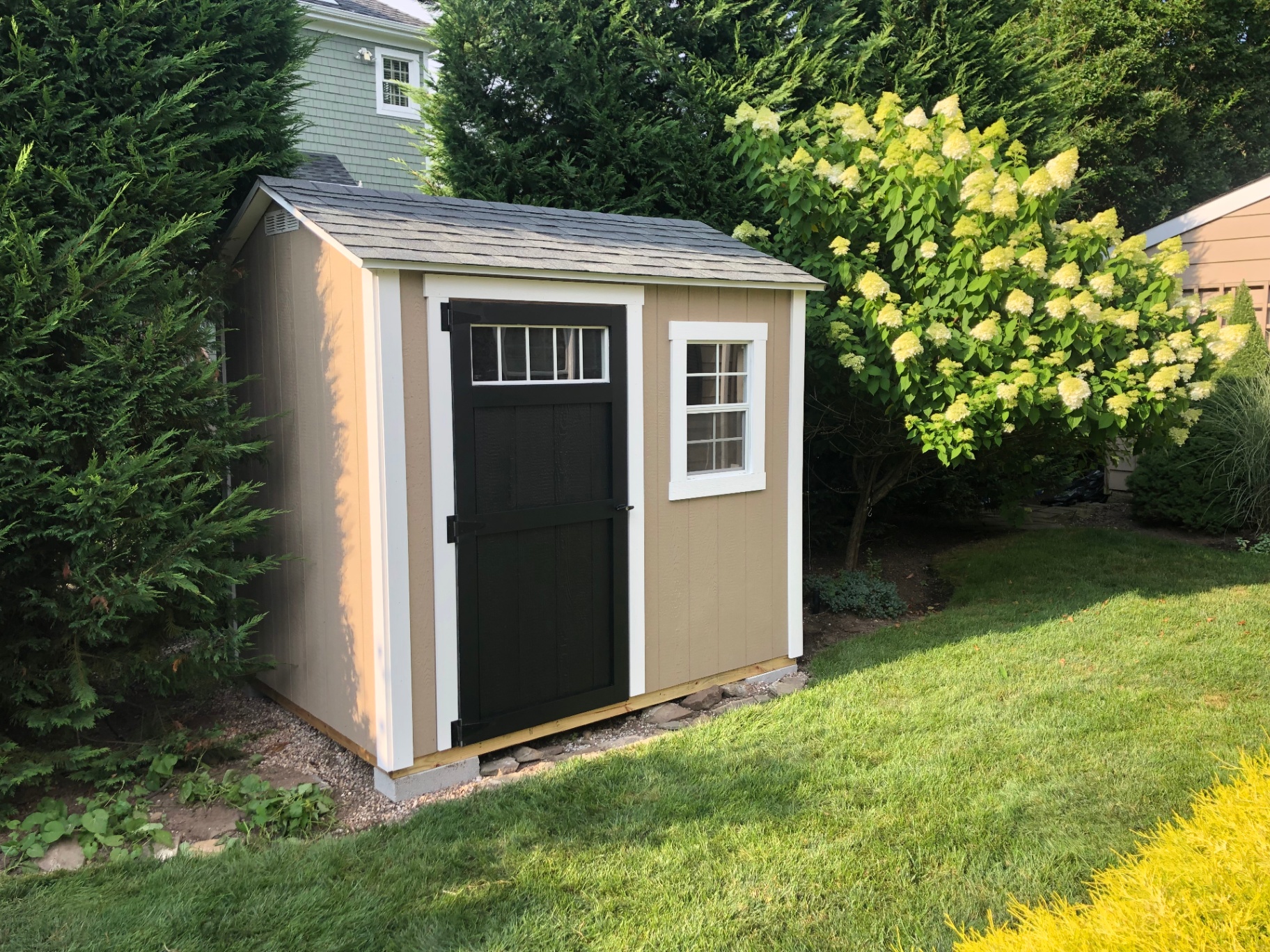 Custom tan storage shed with black door built on-site in Floyds Knobs, Indiana